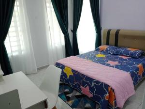 a bedroom with a bed and a table and a chair at Homestay Pinang Tunggal in Sungai Petani