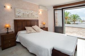 a bedroom with a white bed and a large window at Villa Dos Pinos in Cala d´Or +25 photos