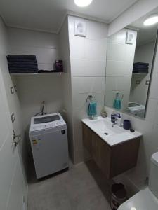 a bathroom with a sink and a toilet and a mirror at La herradura departamento nuevo a pasos de la playa 2 dorm 1 baño in Coquimbo