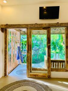 Habitación con una gran puerta de cristal y TV. en Oasis Villas, en Gili Trawangan