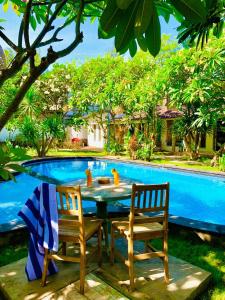 a table and two chairs next to a swimming pool at Oasis Villas in Gili Trawangan