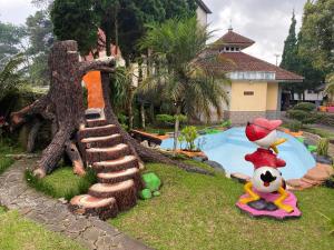 a garden with a statue of a tree next to a pool at Hotel Puspa Sari in Ciater