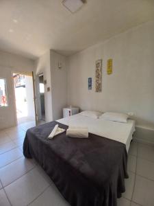 een slaapkamer met een groot bed en een zwarte deken bij Hotel e Pousada Pouso54 in Ubatuba