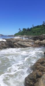 a beach with rocks and the ocean and trees at Pousada Praia Mansa Superagui in Superagui