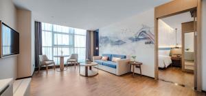 a living room with a blue couch and a bedroom at Shanxi Xiaohe Xincheng Talent Apartment in Taiyuan