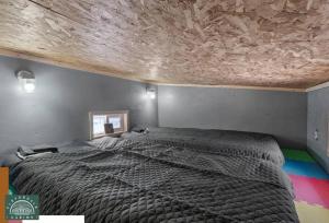 1 dormitorio con 1 cama grande y techo de madera en Blue Tiny Home@Cloverdale Cabins, en Hinckley