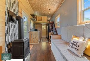 ein Wohnzimmer mit einem Holzofen in einem winzigen Haus in der Unterkunft Blue Tiny Home@Cloverdale Cabins in Hinckley