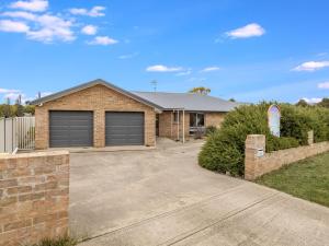 a house with two garage doors and a driveway at 3A Kunama in Berridale