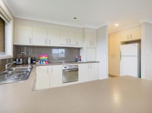 a kitchen with white cabinets and a white refrigerator at 3A Kunama in Berridale