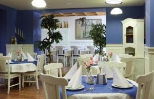 ein Esszimmer mit blauen Wänden und weißen Tischen und Stühlen in der Unterkunft Batory Annex in Krakau