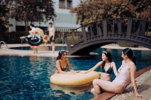 three women sitting in the water in a swimming pool at SC Park Hotel in Bangkok