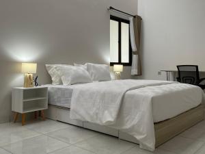 a white bedroom with a large bed with a window at 9 Residence Guesthouse Syariah Cilandak in Jakarta