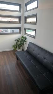 a black couch in a living room with windows at Cerca Reloj Flores Viña in Viña del Mar