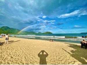 a shadow of a person standing on a beach with a rainbow at Vila Maui in Ubatuba