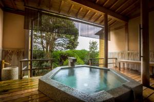 a hot tub in a room with a large window at Hotel Kitanoya in Miyazu
