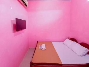 Un dormitorio rosa con una cama y un televisor en la pared. en Papilo House near Stasiun Nganjuk Mitra RedDoorz, en Nganjuk