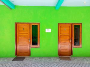 Una pared verde con dos puertas de madera. en Papilo House near Stasiun Nganjuk Mitra RedDoorz, en Nganjuk 6 fotos más