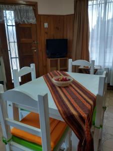 una mesa blanca y sillas con un bol de fruta. en Cómodo monoambiente a 5 minutos del centro! en San Carlos de Bariloche