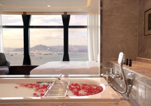 a bathroom with a tub with a bed and a window at One-Eight-One Hotel & Serviced Residences in Hong Kong