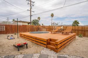 a wooden deck with two chairs and a table at Palm Vista Retreat *Hot Tub/Cowboy Pool/Hammocks* in Joshua Tree