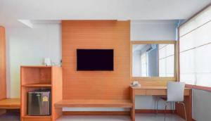 a room with a desk and a tv on a wall at The Little Nest Phuket in Phuket
