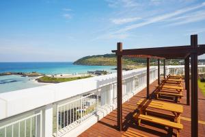 a balcony with wooden chairs and the ocean at Saint Beach Hotel in Jeju