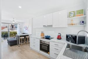 una cucina con armadi bianchi e piano cottura di Alfred Street - Hosted by Burleigh Letting a Gold Coast