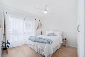 una camera bianca con letto e ventilatore a soffitto di Alfred Street - Hosted by Burleigh Letting a Gold Coast