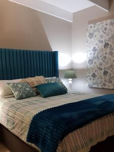 a bedroom with a bed with a blue headboard at Tortuga - Peaceful Holiday Home with Loadshedding Backup in Sedgefield
