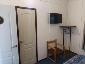 Habitación con puerta, silla y TV. en Hotel Estación Náutica - Aeropuerto, en Punta Arenas