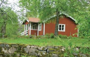 a red house with a stone wall in front of it at 2 Bedroom Stunning Home In Skepplanda in Hålan