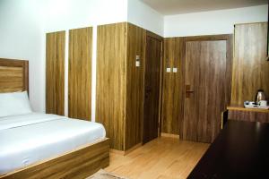 1 dormitorio con cama y armario de madera en Hotel Capitol, en Ikeja