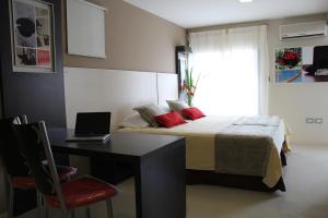 a bedroom with a bed and a desk with a laptop at Sol de Piedra Apart, Suites & Spa in Córdoba