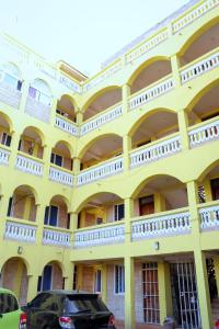 a yellow building with a car parked in front of it at Semo's apartment in Bamburi