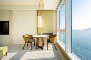 Cette chambre dispose d'une grande fenêtre et d'une table avec des chaises. dans l'établissement The Fullerton Ocean Park Hotel Hong Kong, à Hong Kong