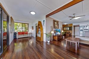 uma sala de estar em plano aberto com pisos em madeira e uma mesa em Airlie Getaway - Airlie Beach em Airlie Beach