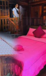 a bedroom with a pink bed with a man in the background at KOB SUK RESORT k7 , k10 in Sichon