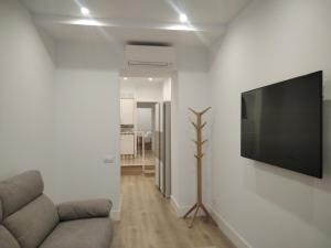 a living room with a couch and a flat screen tv at El PORTON DE LA BELLOTA - CON PARKING GRATIS - EN EL CENTRO DE TOLEDO in Toledo