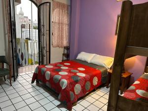a bedroom with a bed with a red comforter at My Family In Monterrey - Hostel in Monterrey
