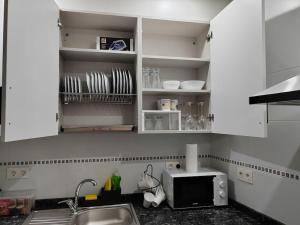 cocina con armarios blancos, fregadero y microondas en Logroño Centro Home, en Logroño