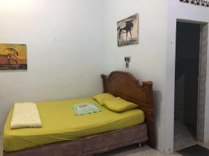 1 dormitorio con 1 cama con sábanas amarillas y cuadros en la pared en Friendjoss Homestay Laugumba RedPartner, en Berastagi