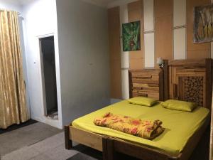 una camera da letto con un letto con una coperta gialla sopra di Friendjoss Homestay Laugumba RedPartner a Berastagi