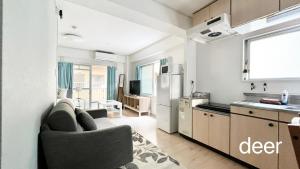 een keuken en een woonkamer met een bank en een koelkast bij Maison Milano Nakatsu Apartment in Osaka