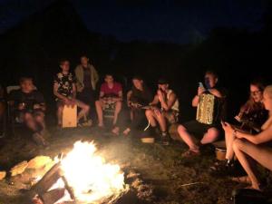 grupa ludzi siedzących przy ogniu w obiekcie Camping La cour d'Enchère w mieście Saint-Palais