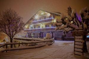 un edificio coperto di neve di notte di Hotel Le Christiania a Les Contamines-Montjoie