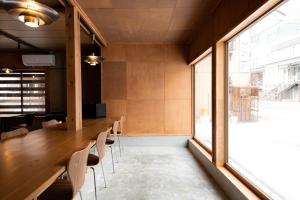 湯沢町にあるLittle Japan Echigoの大きな窓のある客室で、長いテーブルと椅子が備わります。