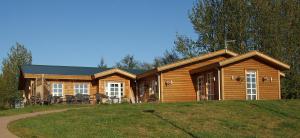a large log cabin with a porch and a lawn at Guesthouse Fludir - Grund in Fludir