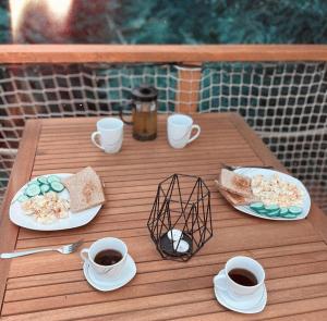 a wooden table with plates of food and cups of coffee at Kousek klidu in Oldřichov v Hájích
