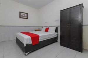 a bedroom with a bed with a red blanket on it at RedDoorz near Stasiun Malang Kota Lama 2 in Malang +16 photos