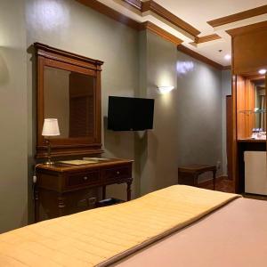 a bedroom with a bed and a dresser and a television at Herald Suites in Manila